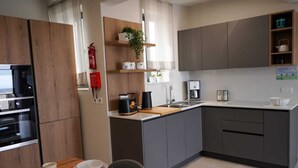 Eine moderne Küche mit grauen Schränken, einer Holzauskleidung und einem Essbereich mit Tisch für zwei Personen.