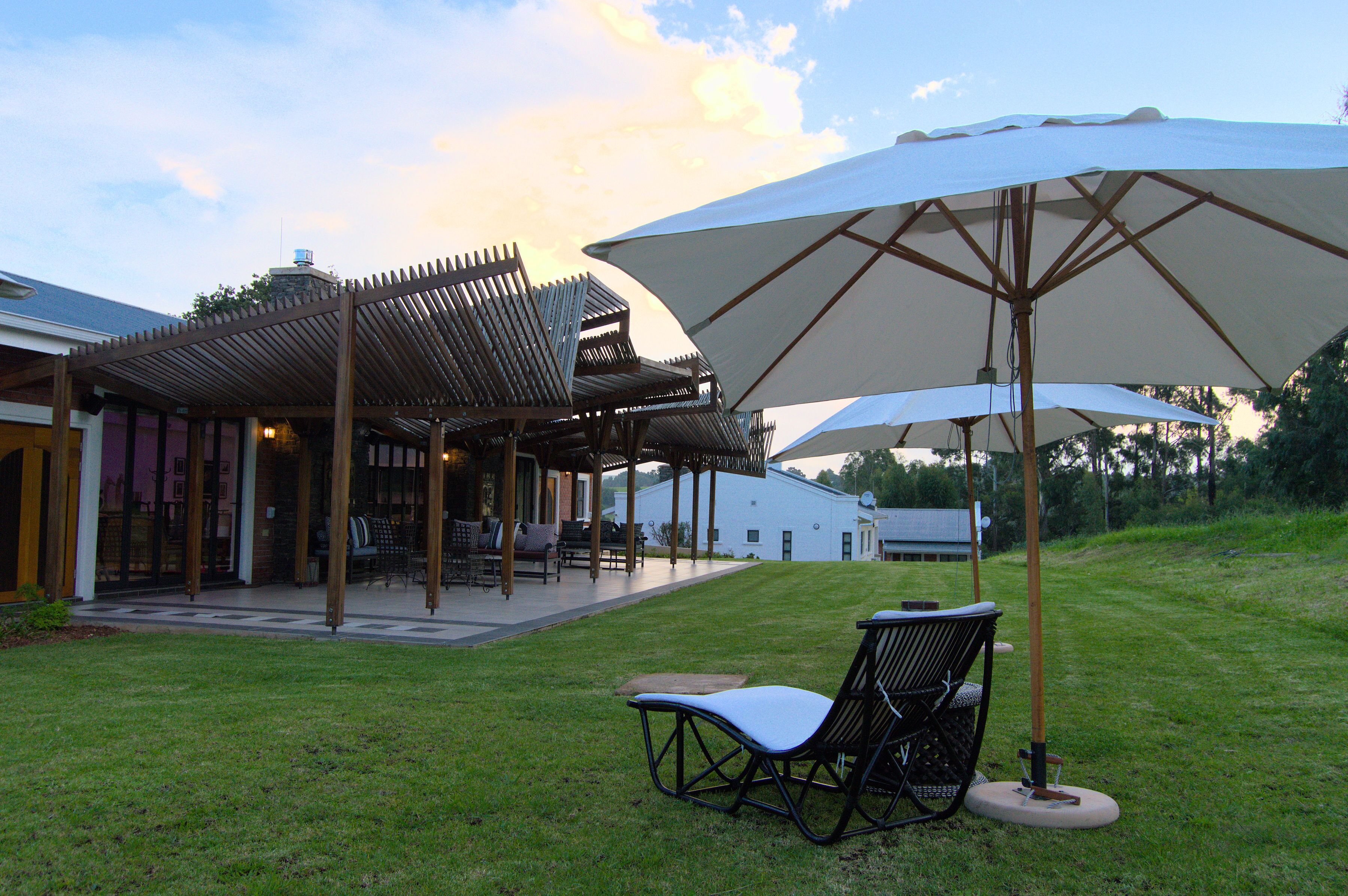 Un área de patio al aire libre con pérgola, asientos y una sombrilla grande.