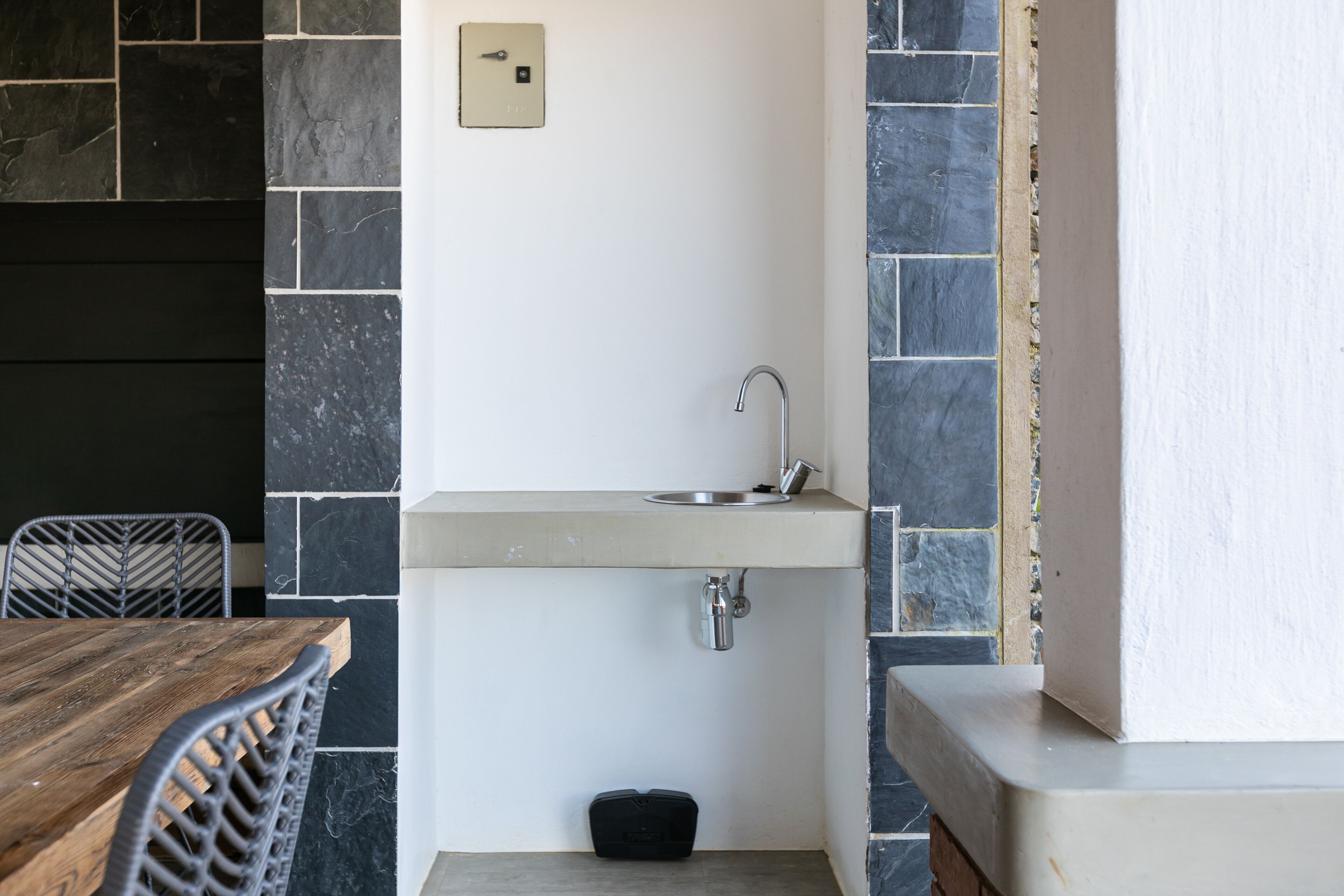 A compact kitchen with a built-in sink, a small countertop, and a chair.