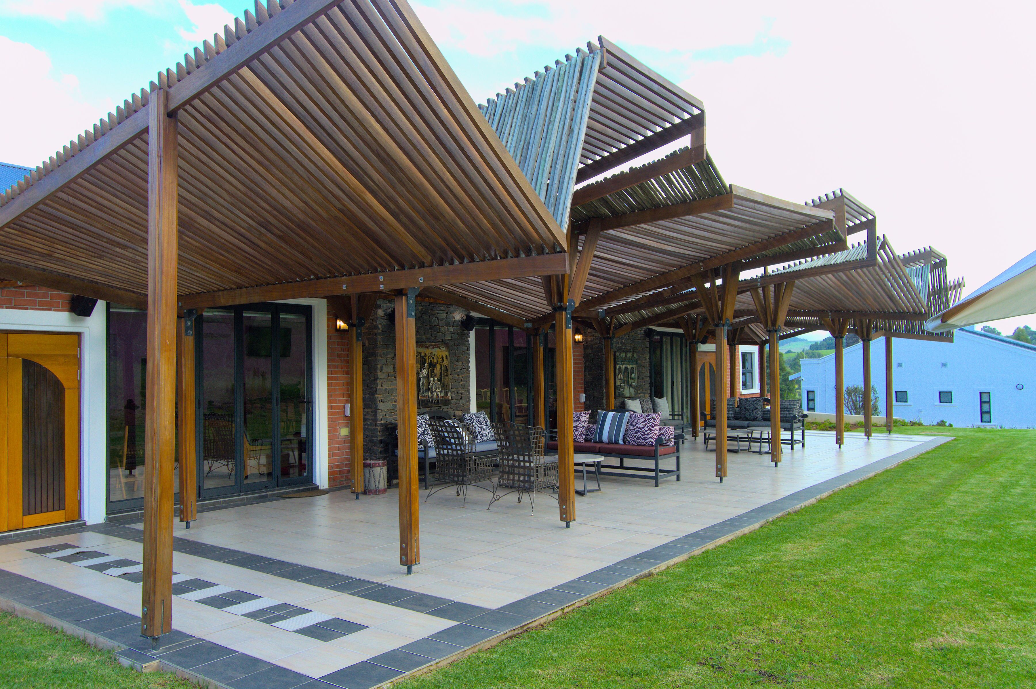 A covered outdoor seating area with wooden beams and a stone wall backdrop.