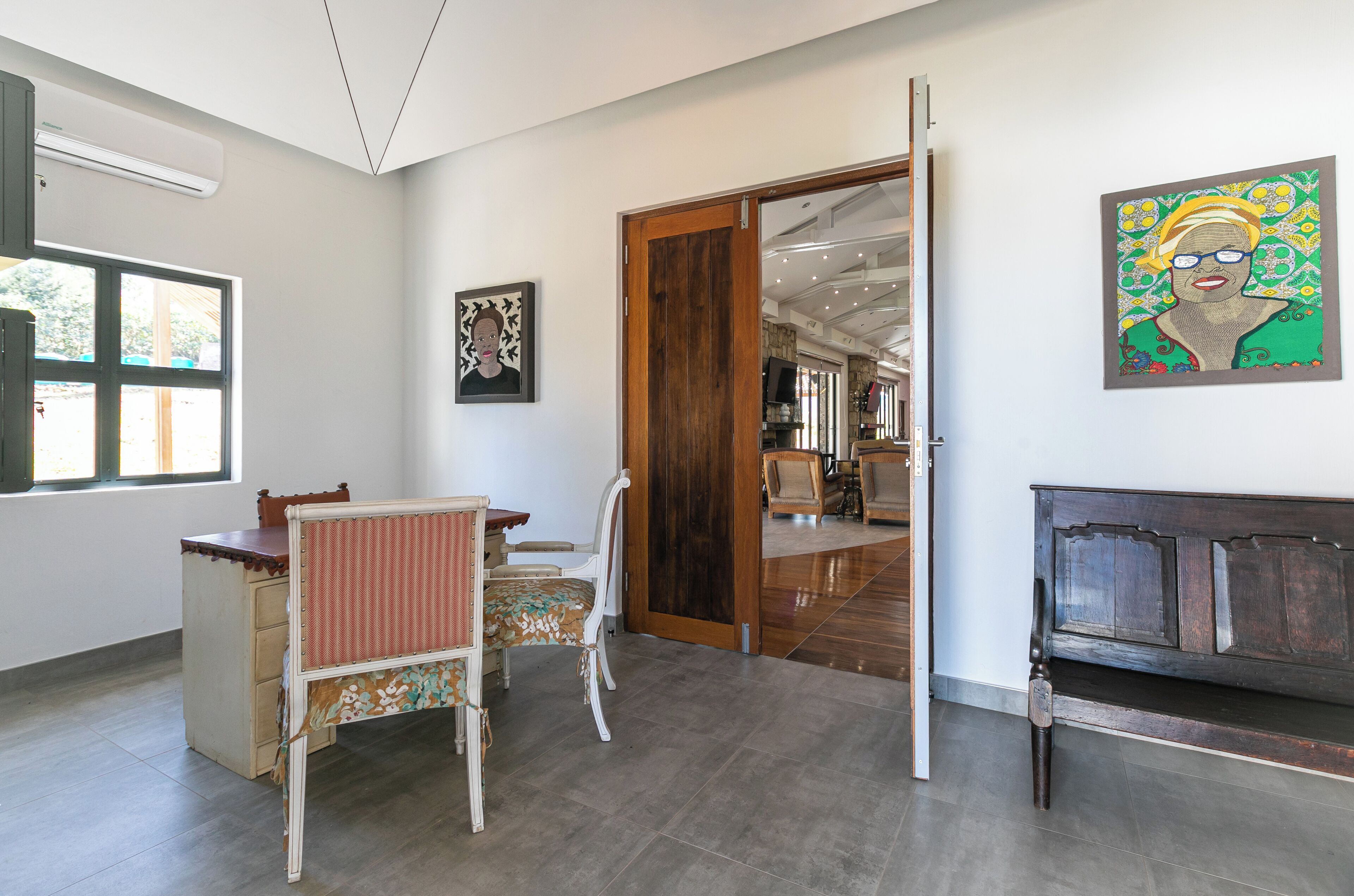 A room with a wooden bench, a desk with a chair, and a door leading to another area.