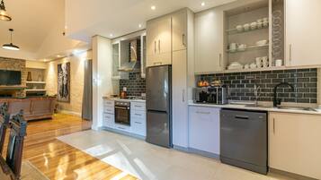 A modern kitchen with stainless steel appliances, white cabinetry, and a black tiled backsplash.