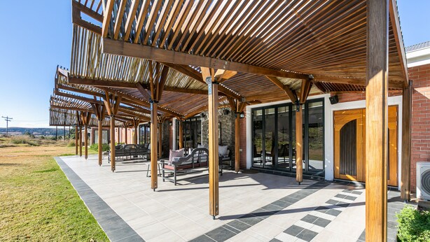 Un espace extérieur aménagé, abrité et doté de poutres en bois et de carreaux de pierre.