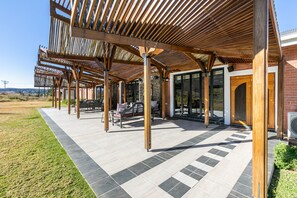 A covered outdoor seating area with wooden beams and stone tiles. - Bali and Eva Midlands (Zenzani)