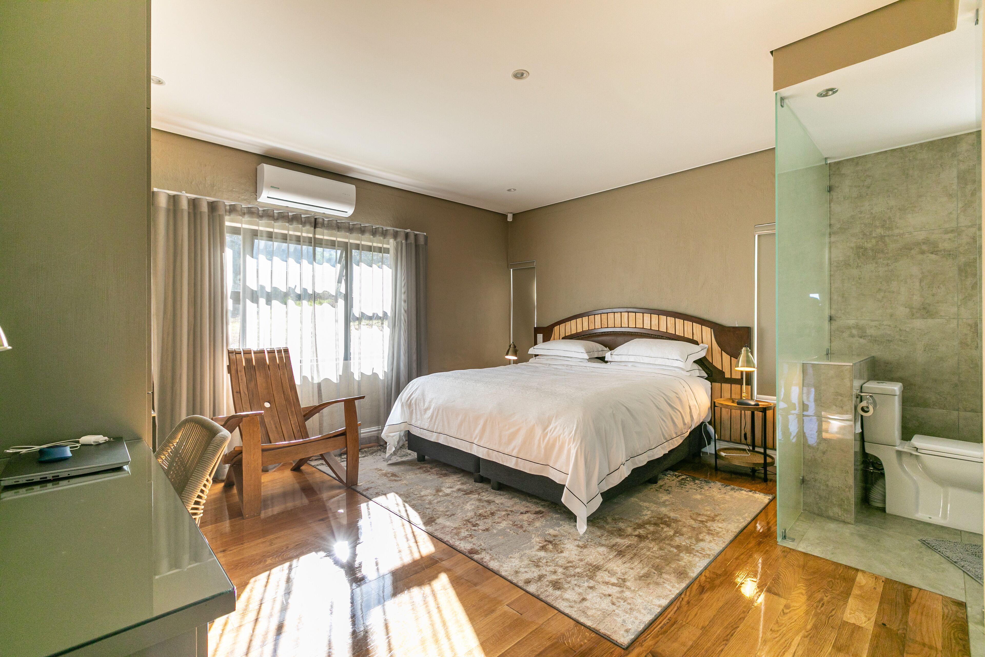Hotelkamer met een bed, een bureau, een stoel, een douche en een badkamer met glazen wanden.