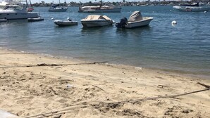 Una spiaggia sabbiosa con diverse imbarcazioni ormeggiate in acque calme.