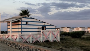 Ein Gebäude am Strand mit Wellblechdach, einem kleinen Fenster und einem Holzzaun.