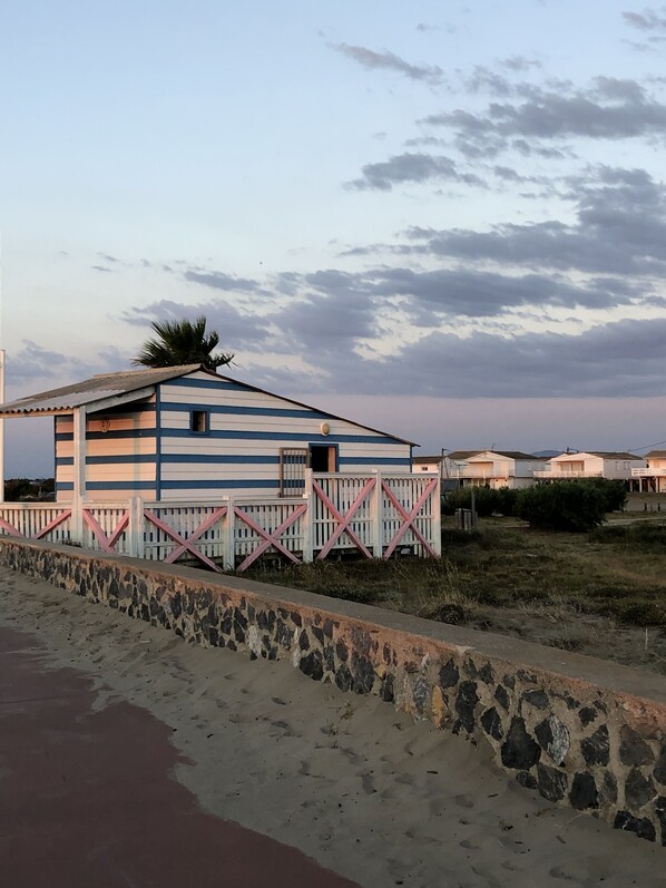 A beachside building with a corrugated metal roof, a small window, and a wooden fence.