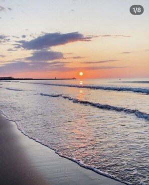 A beach at sunset with waves gently lapping the shore.