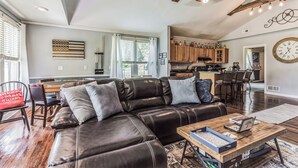 A modern living room with a leather sectional sofa, wooden coffee table, and a dining area with a wooden table and chairs. - New Hope Bourbon Stop- historic home, peaceful spot in heart of Bourbon country (New Hope)