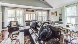 A spacious living room with a leather sectional sofa, a dining table, and a large window with blinds. - New Hope Bourbon Stop- historic home, peaceful spot in heart of Bourbon country (New Hope)