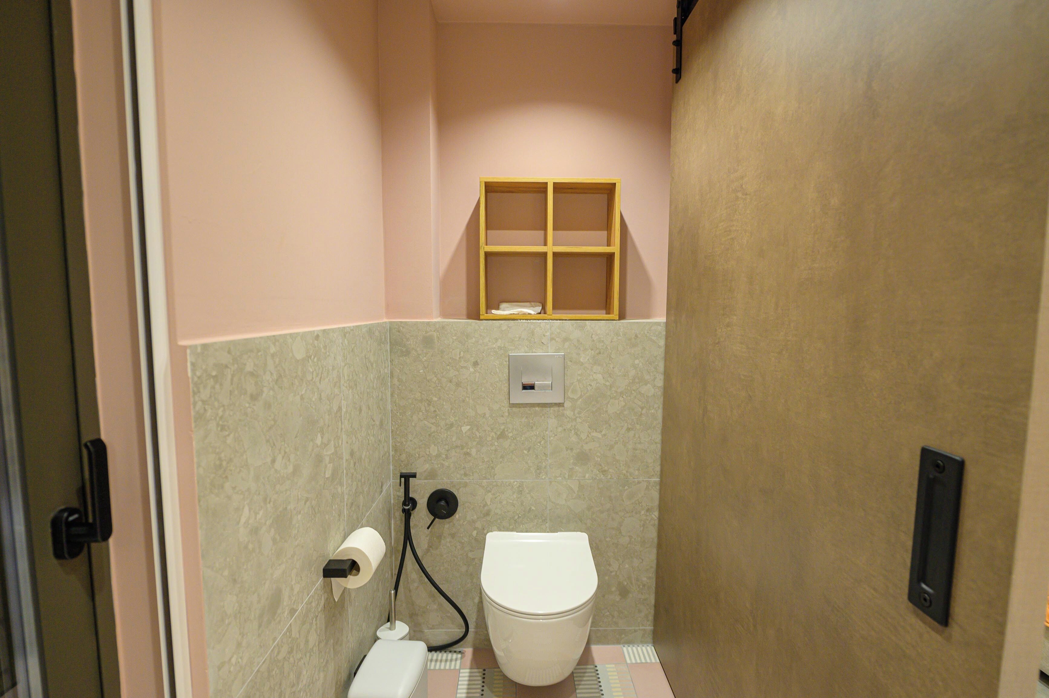 A small bathroom with a toilet, a shelf, and a towel rack.