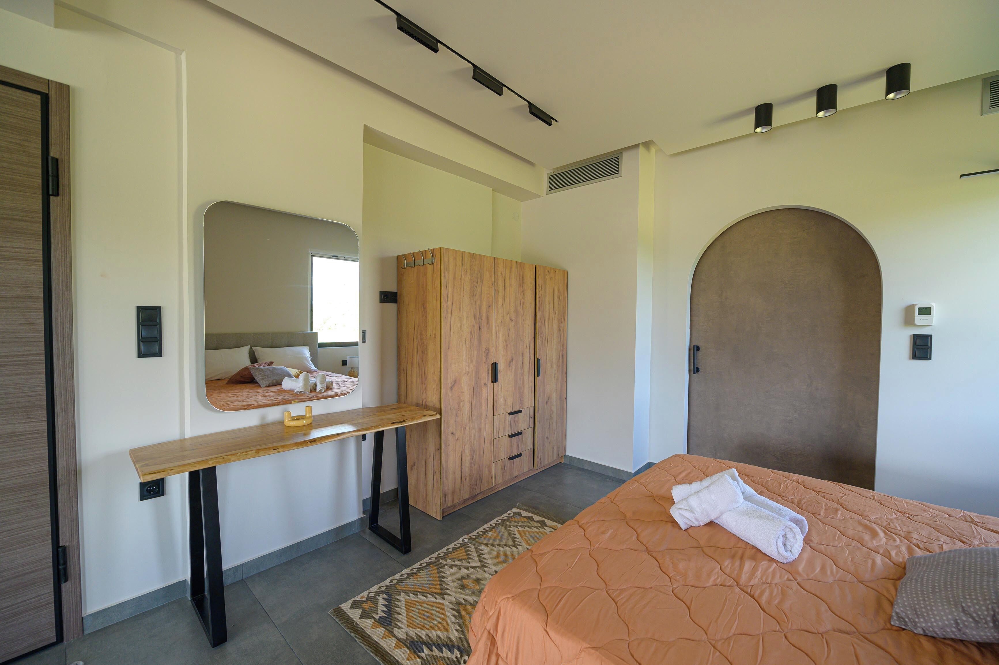 A modern bedroom with a bed, a wooden wardrobe, a mirror, and a small table.