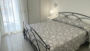A bedroom with a bed, a nightstand, a lamp, and a door.