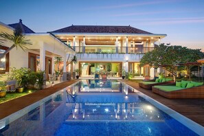 A two-story house with a swimming pool, outdoor seating, and a balcony.