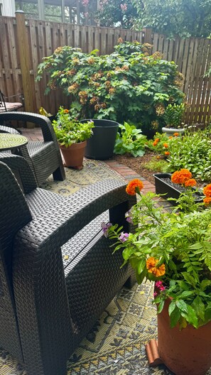 Een terras met rieten meubilair en plantenpotten.