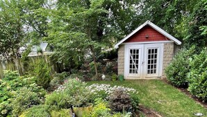 Un jardin avec différentes plantes en pot et un petit abri de jardin.