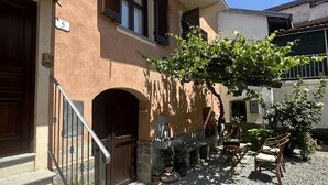 A building with a stone staircase leading to a wooden door, a balcony with a metal railing, and a row of potted plants along the front. - Censo Guest House : are you ready for your next adventure? (Marsaglia)