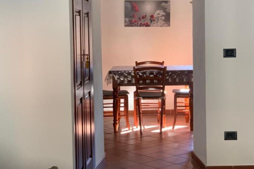 A dining area with a table and chairs, a painting on the wall, and a tiled floor.
