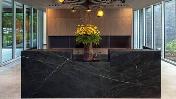 A modern reception desk with a marble top, a wooden cabinet, and a vase of sunflowers.