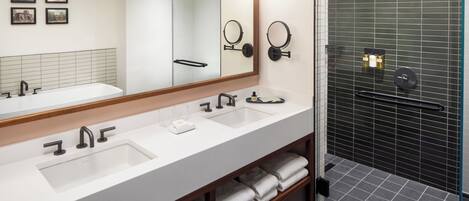 Une salle de bain moderne avec un grand miroir, deux lavabos et un espace douche.