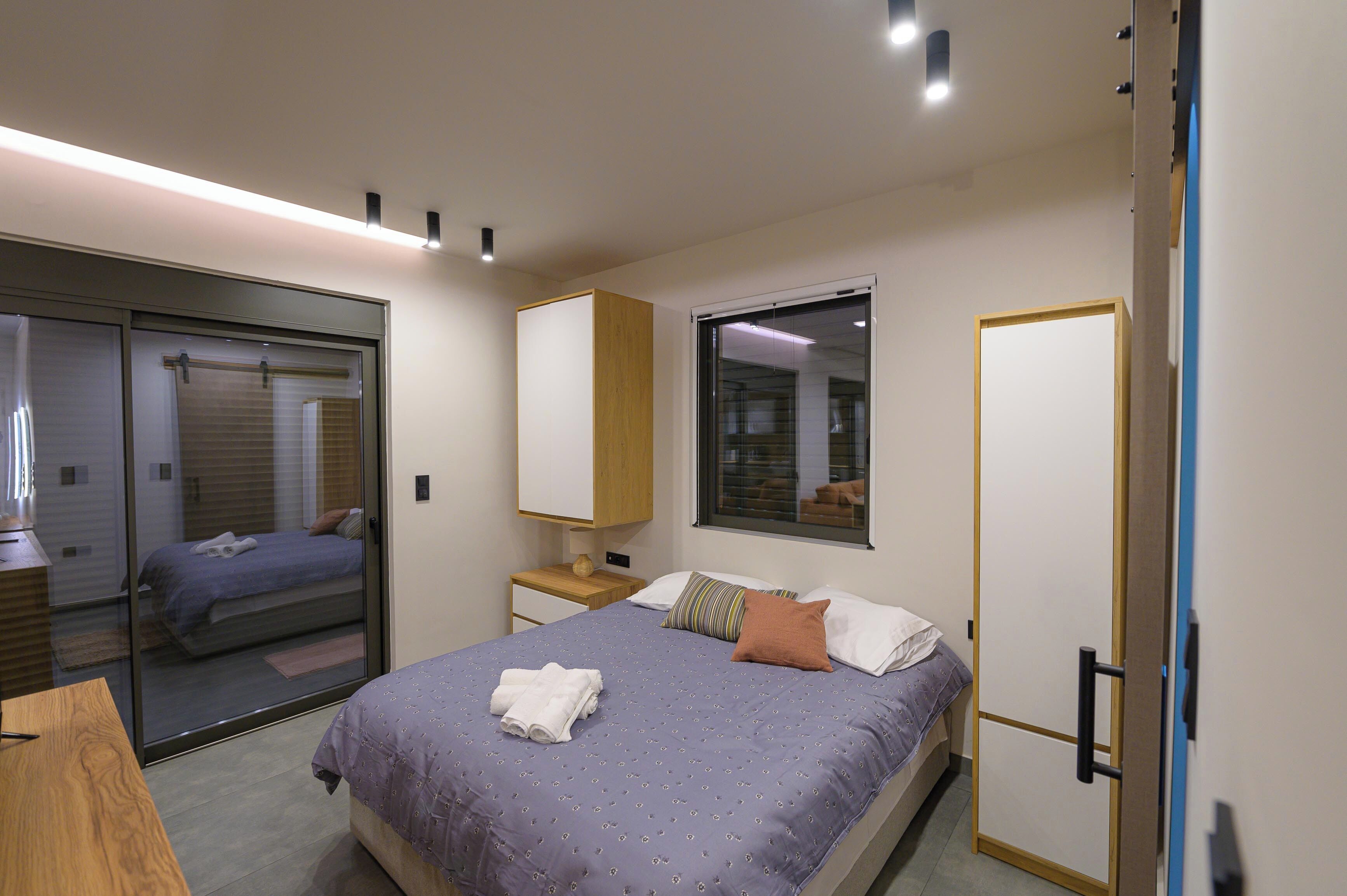Een slaapkamer met een bed, een nachtkastje, een spiegel en een schuifdeur naar een badkamer.