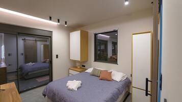 Een slaapkamer met een bed, een nachtkastje, een spiegel en een schuifdeur naar een badkamer.