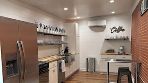 A modern kitchen with stainless steel appliances, wooden flooring, and a coffee-themed decor. - The Apalachicola Train Depot (Apalachicola)