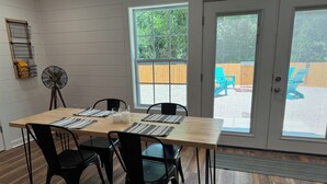 A dining area with a wooden table, black chairs, and a fan. - The Apalachicola Train Depot (Apalachicola)