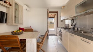 A modern kitchen with wooden cabinets, a stainless steel sink, and a dining area with a wooden table and chairs. - 3844 Villetta Della Poesia by Barbarhouse (Melendugno)