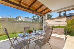 An outdoor patio with a table set for two, a swing chair, and a view of the surrounding area. - 3844 Villetta Della Poesia by Barbarhouse (Melendugno)