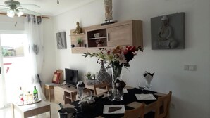 A dining area with a table set for two, a vase with flowers, and a statue on the wall. - El Campello Deborah. à 10 Minutes à Pied de la Plage et 5 Minutes du Centre (El Campello)