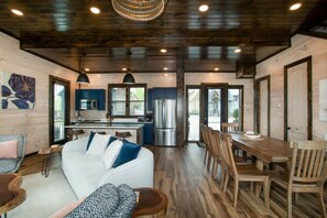 Relax in this open-plan living space with a kitchen area, featuring a sofa, dining table, and modern appliances.