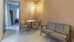 Un espacio habitable compacto con un sofá, dos sillones, una mesita redonda y aire acondicionado instalado en el techo.