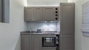 Una cocina compacta con armarios grises, un horno empotrado y una encimera de granito.