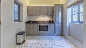A compact kitchen with grey cabinets, a stainless steel oven, and a tiled floor. - Mid-Century Retro Suite (Floriana)