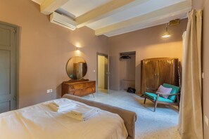 A bedroom with a bed, dresser, mirror, and a chair.