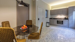A modern kitchen with grey cabinets, a stainless steel range hood, and a black trash bin. - Mid-Century Retro Suite (Floriana)