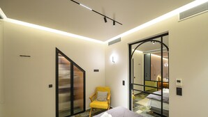 Una habitación de hotel con una cama, una silla, un espejo y una puerta corredera.