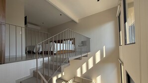 A modern interior with a staircase leading to a bedroom, a sofa, and a TV.