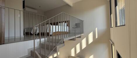 Un interior moderno con una escalera que lleva a un dormitorio, un sofá y un televisor.