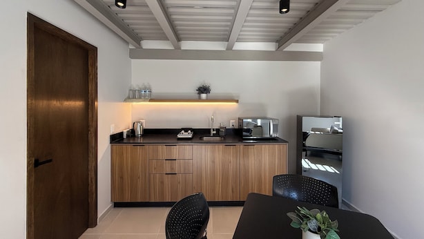 A modern kitchen with wooden cabinets, a black countertop, and a dining area with a table and chairs.