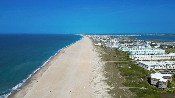 An aerial view of a coastal area with a long sandy beach, a row of beachfront hotels, and a clear blue sky. - Atlantic Beach Getaway Spacious 3-Level Condo: Walk to the Beach & Pool (Atlantic Beach)