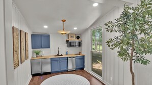 Una cocina moderna con armarios azules, una encimera de madera y una alfombra redonda blanca.