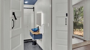 Un pasillo con puertas blancas, un lavabo azul y un espejo.