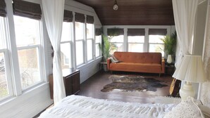 Ein Zimmer mit einem Bett, einem Sofa, einer Lampe und einer Gitarre.