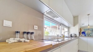 A modern kitchen with a wooden countertop, stainless steel appliances, and a large window providing natural light. - Villa with private pool and garden (Mar de Cristal)