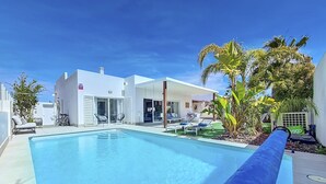 A modern pool area with a clear blue pool, lounge chairs, and a covered seating area. - Villa with private pool and garden (Mar de Cristal)