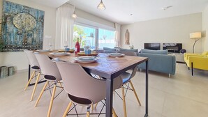 A modern living room with a dining area, a large window, and a TV. - Villa with private pool and garden (Mar de Cristal)