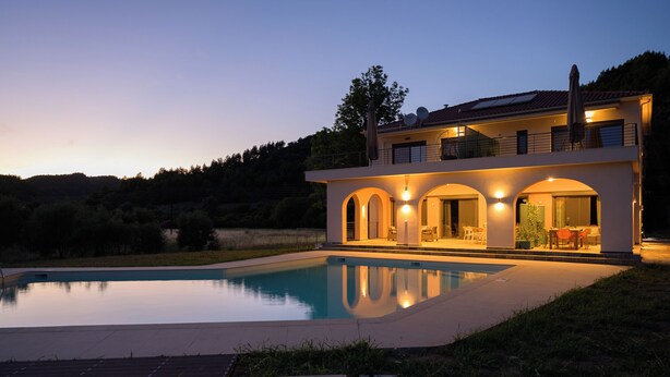 Una casa moderna con piscina, ventanas amplias y un balcón.